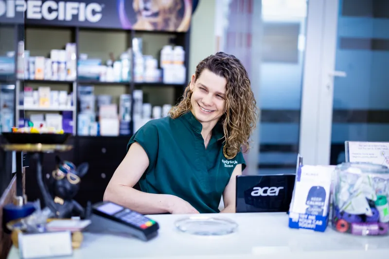 Gydytoja Ilona šypsosi klinikos registratūroje prie kompiuterio